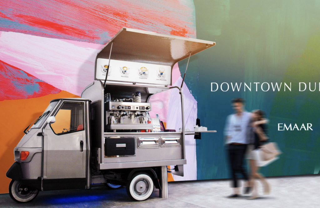 Small branded promotional truck parked beside a colorful mural with “Downtown Dubai” and Emaar signage.