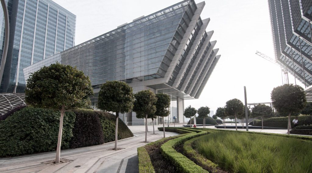 Cluster of modern glass skyscrapers with reflective surfaces and sharp architectural lines.