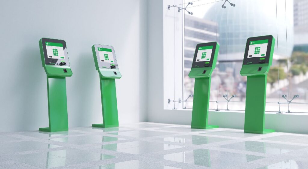 Man using a row of green self-service kiosks inside a modern, brightly lit interior with “BRASH” and Absher branding on the wall.