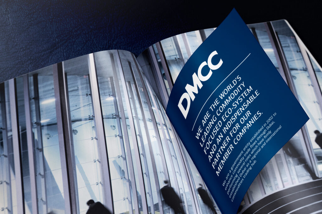 Close-up of a contemporary glass building with a curved facade and a DMCC branded sign.